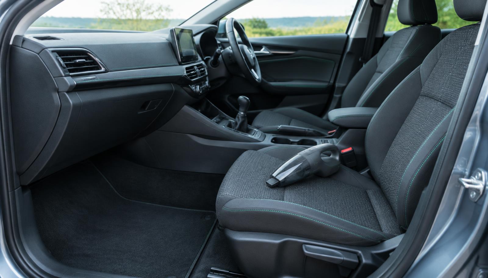A clean car interior with a compact handheld vacuum on the front seat